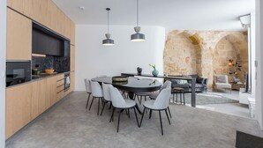 Una cucina moderna con zona pranzo, caratterizzata da una parete in pietra e un angolo salotto accogliente con divano e poltrone.