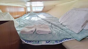 Een compacte, goed verlichte kamer met een enkel bed, een raam en een houten hoofdbord.