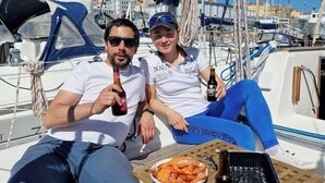 Twee personen in een boot met een tafel waarop eten en drinken staan.