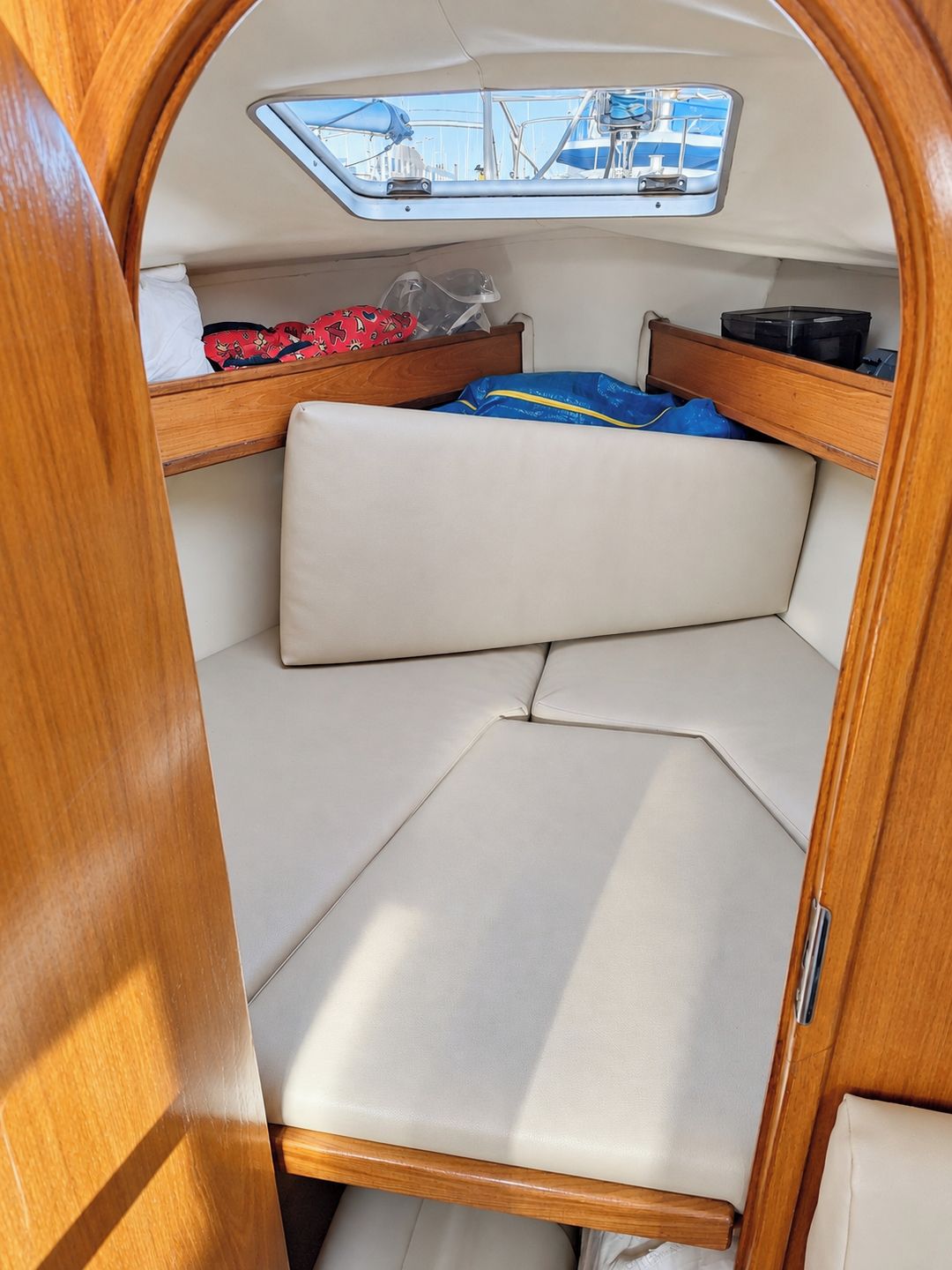 A compact interior with a bunk bed, a small table, and a window with a view of boats.