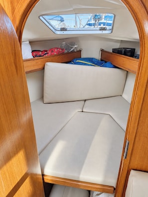 Een compact interieur met een stapelbed, een klein tafeltje en een raam met uitzicht op boten.