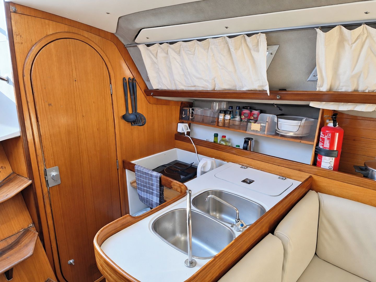 A compact kitchenette with a sink, stove, and storage shelves.