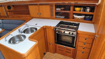 Een kleine keuken met een kookplaat, spoelbak en kastjes.