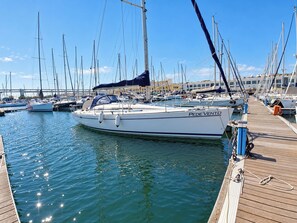 Un port de plaisance où sont amarrés de nombreux voiliers, une jetée en bois et un ciel dégagé.