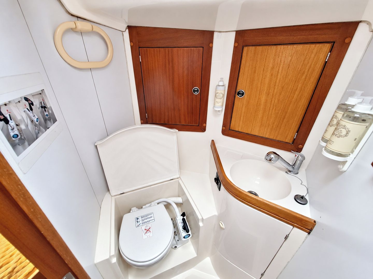 A compact bathroom with a toilet, sink, and wooden cabinets.