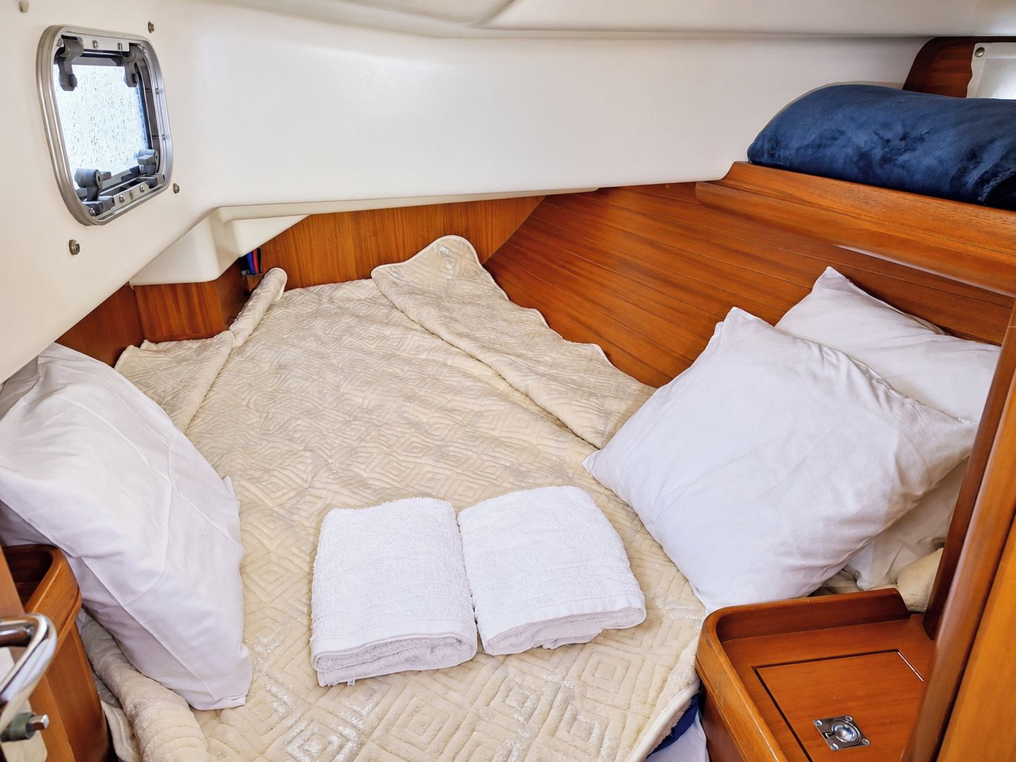 Ein kleines Ferienhäuschen mit einem Bett, Kissen und einem ordentlich gefalteten Handtuch.