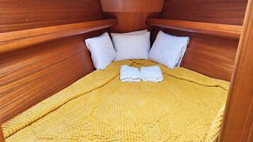 A compact bed with a yellow textured blanket and white pillows in a wooden cabin-style room.
