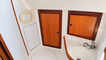 A compact bathroom with a toilet, sink, and shower.