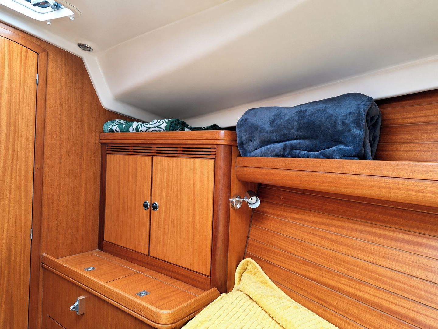 A compact cabin with wooden cabinetry, a bench, and a small overhead shelf.