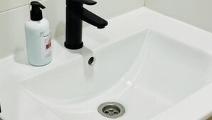Ein weißes Waschbecken mit einem schwarzen Wasserhahn und einer Seifenspender.