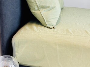 A close-up of a bed with a light-colored mattress and a pillow.
