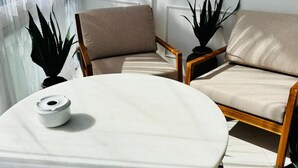 Ein sonnendurchflutetes Zimmer mit einem runden Tisch, zwei Stühlen und Topfpflanzen.