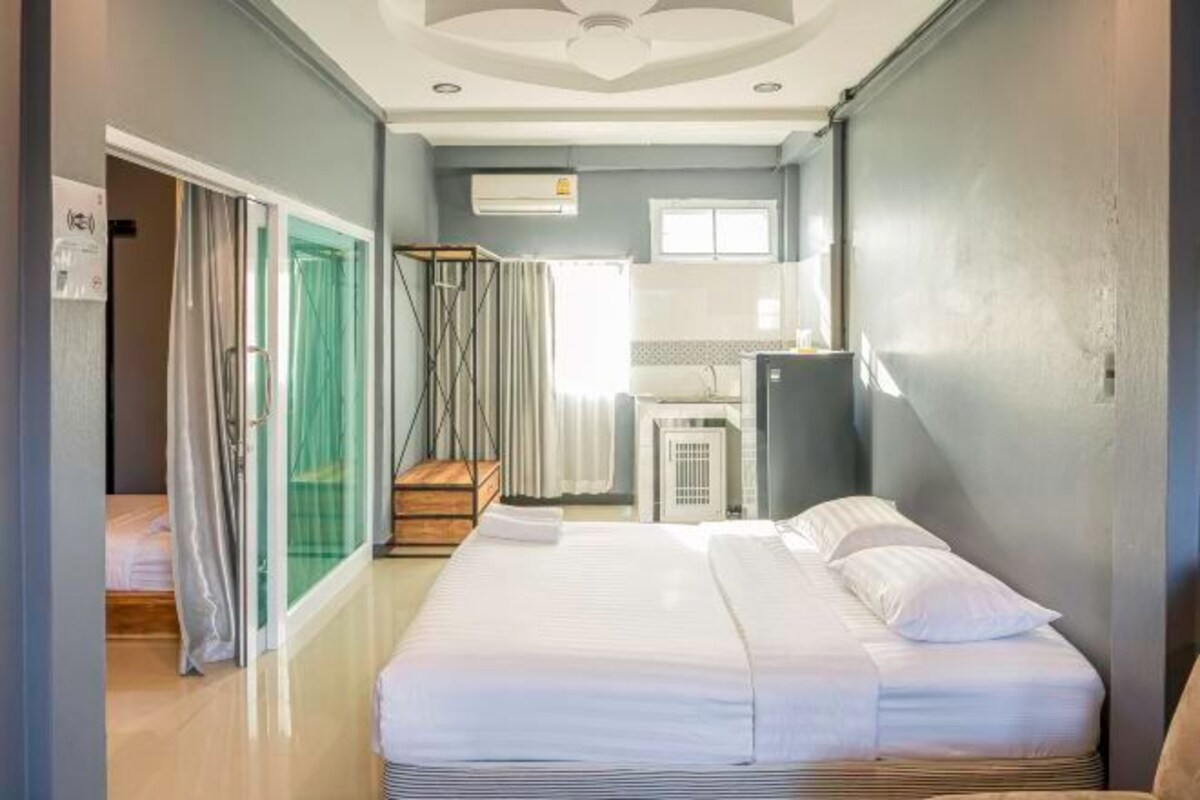A hotel room with a bed, a desk, a chair, a window, and a door.