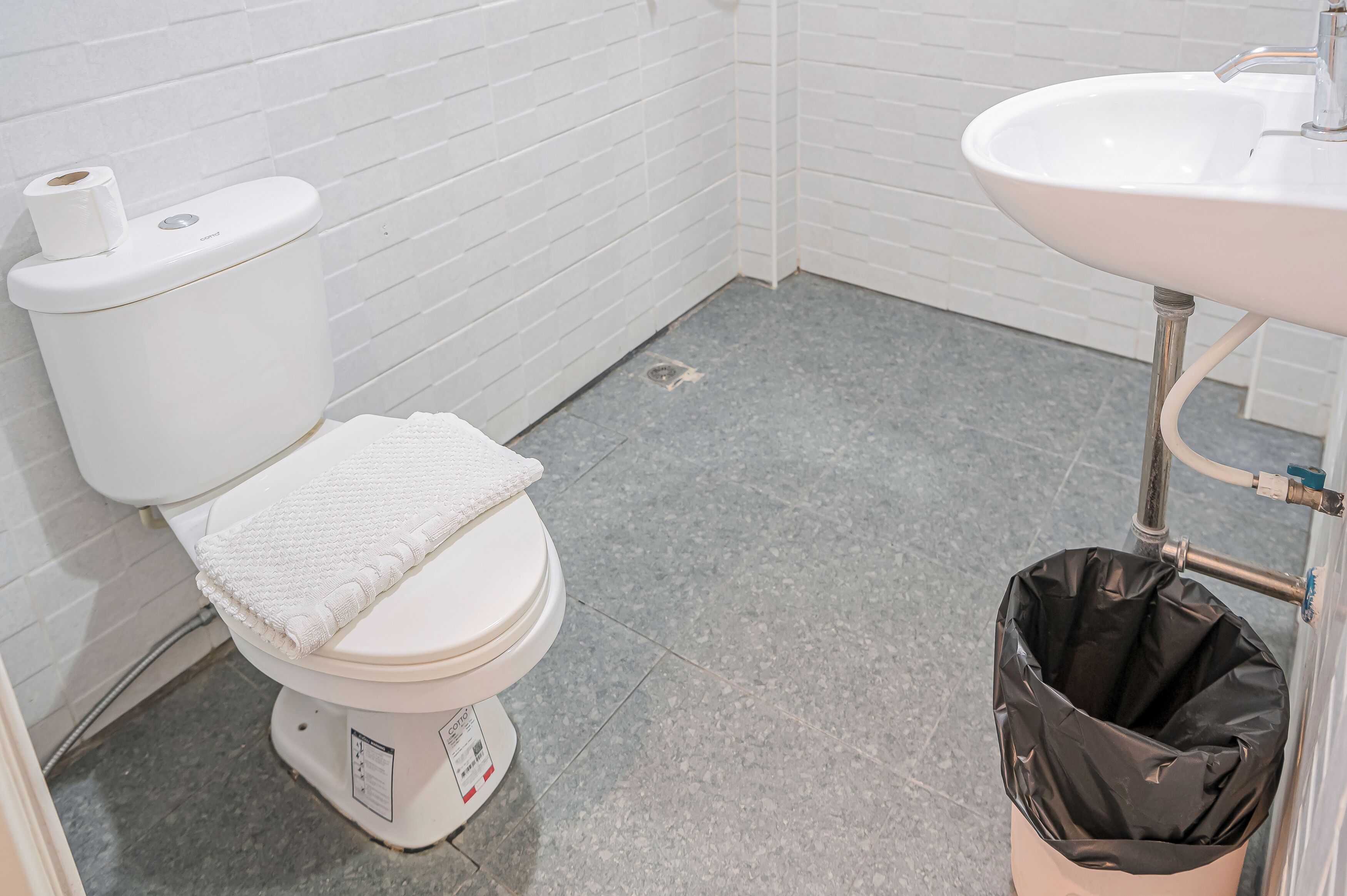 A small bathroom with a toilet, a sink, and a trash bin.