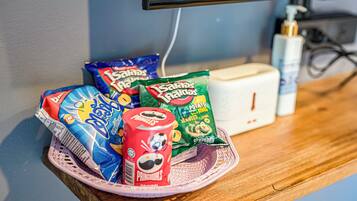 A snack basket with chips and a can of Pringles on a wooden table.