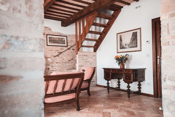 A rustic room with exposed brick walls, wooden furniture, and a herringbone-patterned floor.
