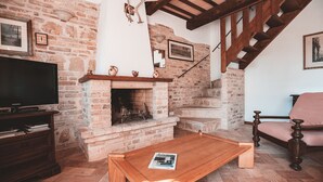 A cozy living room with a fireplace, wooden furniture, and a staircase. - Torre di Palme apartment with panoramic terrace and pool -5 minutes from the sea (Marche)