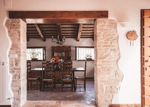 Un comedor rústico con una mesa y sillas de madera, un candelabro y una pared de piedra.