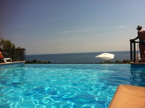 A clear blue pool with a view of the ocean.