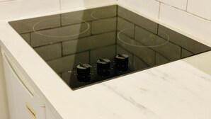Ett kök med en svart induktionshäll och en vit bänkskiva i marmor.