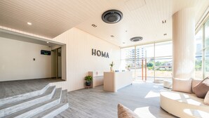 A modern hotel lobby with a reception desk, a seating area, and a staircase leading to the upper floor. - HOMA Si Racha (Si Racha)