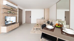 A modern living room with a flat-screen TV, wooden shelves, a dining table with chairs, and a large mirror. - HOMA Si Racha (Si Racha)