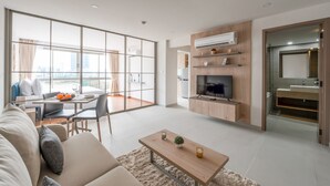 A modern living room with a sofa, coffee table, TV, and a dining area with a table and chairs. - HOMA Si Racha (Si Racha)