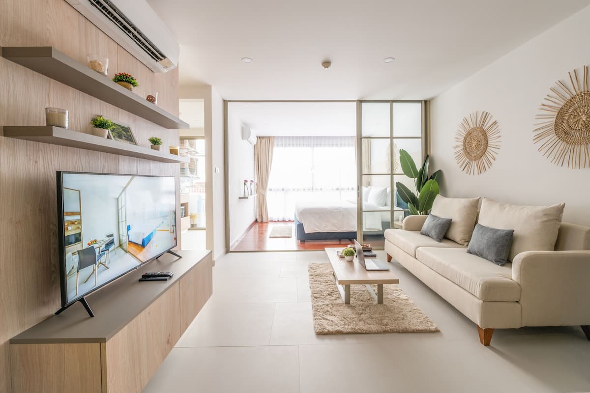 A modern living room with a flat-screen TV, a sofa, a coffee table, and a large window.