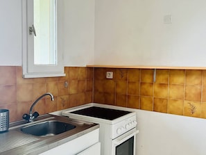 Une cuisine équipée d’un évier, d’une cuisinière et d’une fenêtre située au-dessus de l’évier.