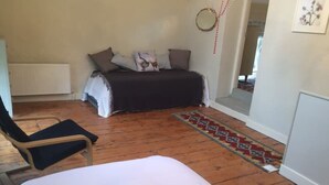 A bedroom with a bed, a chair, a patterned rug, and a radiator.