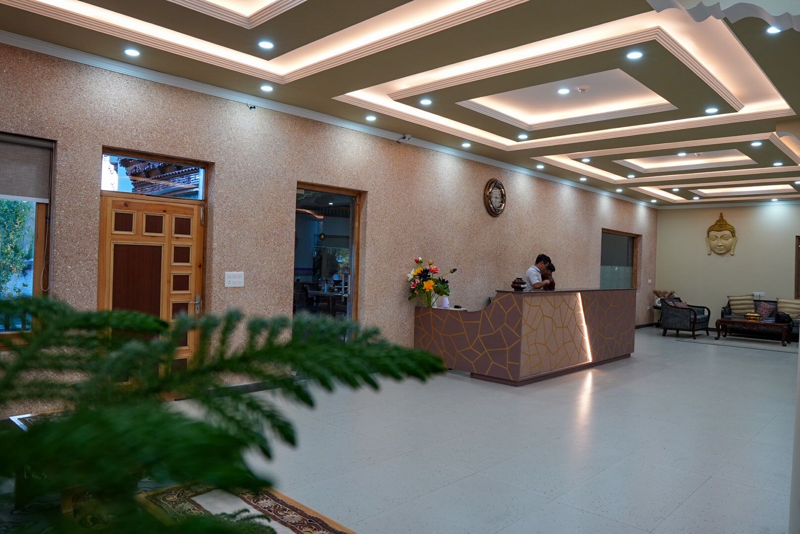 A reception area with a receptionist desk, a Buddha statue, and a large window with a view.