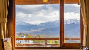 A room with a large window offering a mountain view. - Hotel Karma Residency (Leh)