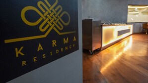A reception desk with a modern design, a logo above it, and a wooden floor. - Hotel Karma Residency (Leh)