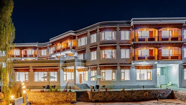 A multi-story hotel with balconies, a stone facade, and outdoor seating areas. - Hotel Karma Residency (Leh)