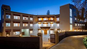 A multi-story hotel with a central courtyard, featuring a grand entrance with a wooden door and a staircase leading to the upper floors.