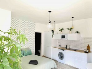A compact, modern apartment with a bed, a washing machine, a microwave, and a small kitchen area. - Rooftop Apartment with Stunning Views in Málaga - Ideal for Beach Lovers (Torremolinos)