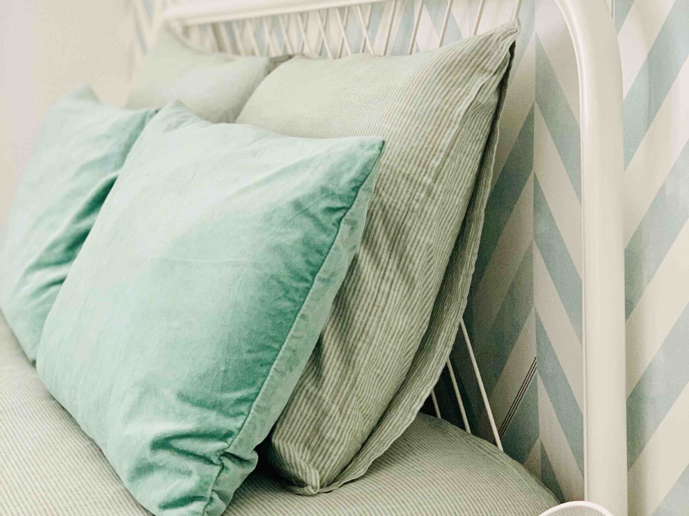 A bed with a white metal frame and a green upholstered headboard.
