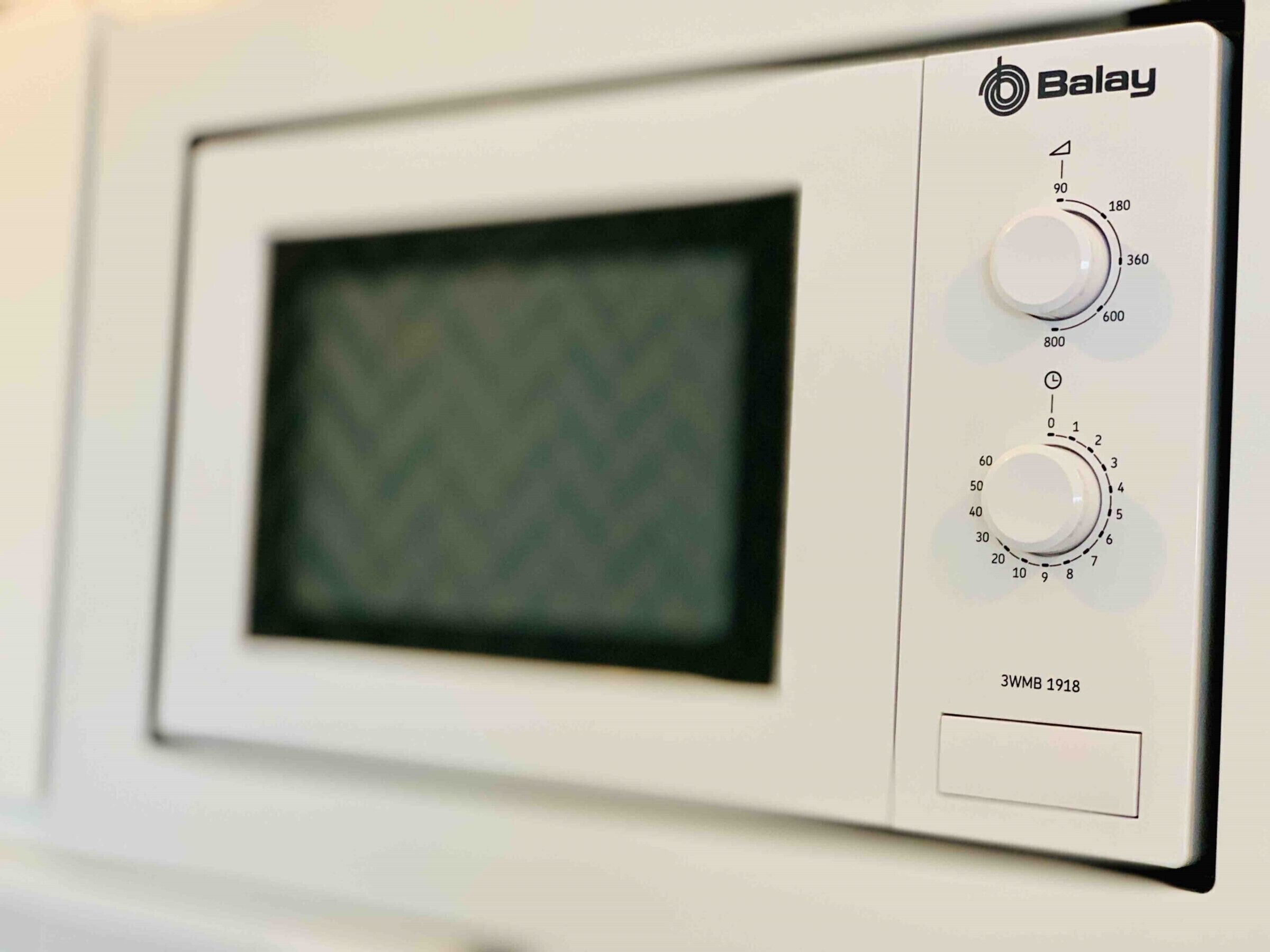 A microwave with a control panel, including a digital display and two dials.