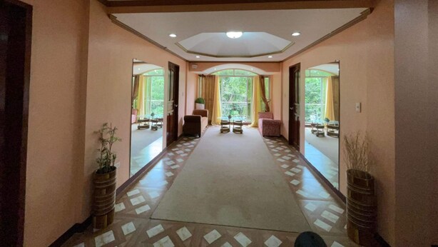 A hallway with a patterned floor, large windows, and a central seating area. - Casa Venicia Caticlan (Boracay Island)