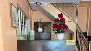A reception desk with a 'No Smoking' sign, a bench, a staircase, and a potted plant with red roses. - Casa Venicia Caticlan (Boracay Island)