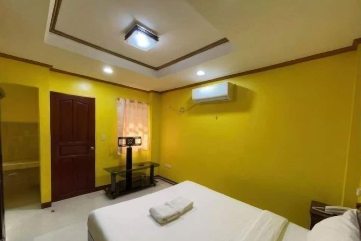 A hotel room with a bed, a desk, a mirror, and a window with curtains.