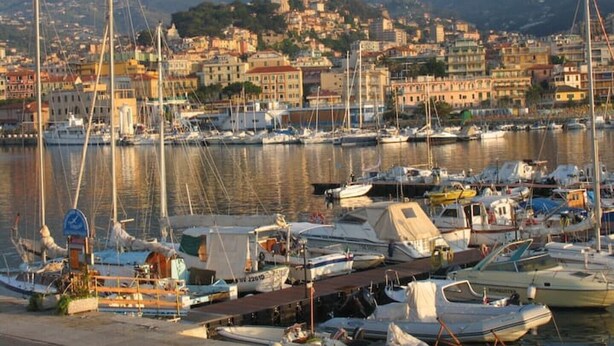A marina with boats docked, a cityscape in the background, and mountains. - Cristina Home "Town Center" (Sanremo)