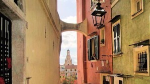 A narrow alleyway with buildings on either side, a visible bell tower in the distance, and a hanging flower pot. - Cristina Home "Town Center" (Sanremo)