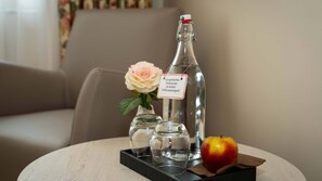 A bottle of water, a rose, a glass, and an apple on a round table. - Boutique Hotel Rosengarten Hamburg (Hamburg)