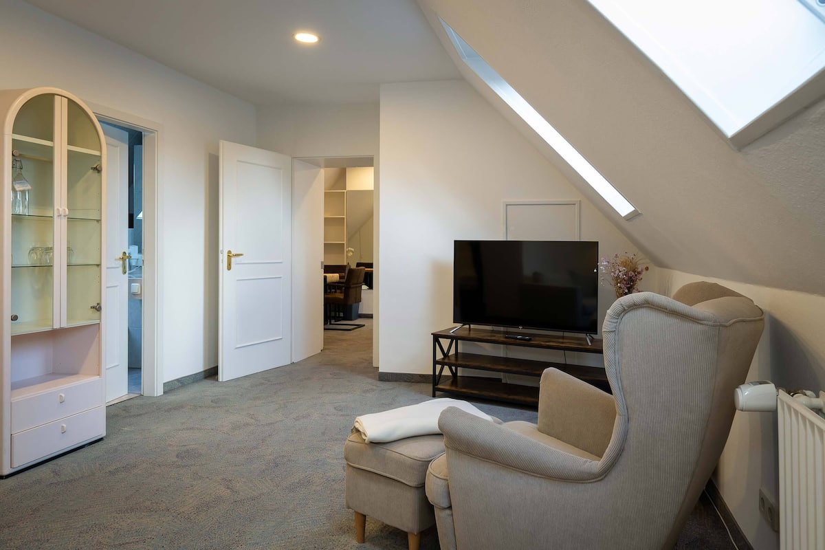 A modern living room with a television, a sofa, and a glass cabinet.