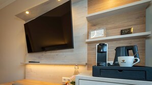 Una habitación de hotel moderna con una televisión de pantalla plana, una cafetera y una taza en la encimera.