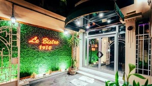Uma entrada com parede verde e um letreiro de neon que diz "Le Bistro 1910".