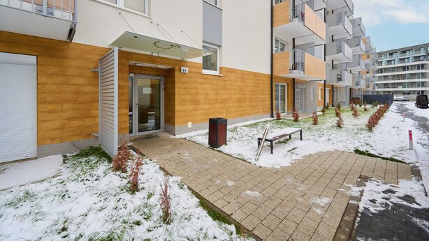 A modern apartment building with a wooden facade, a glass entrance, and a paved walkway. - Sunny Apartment | Balcony and Private Parking (Wrocław)