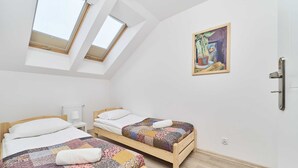 A room with two wooden beds, a skylight, a radiator, and a painting on the wall. - Sunny Apartment | Balcony and Private Parking (Wrocław)