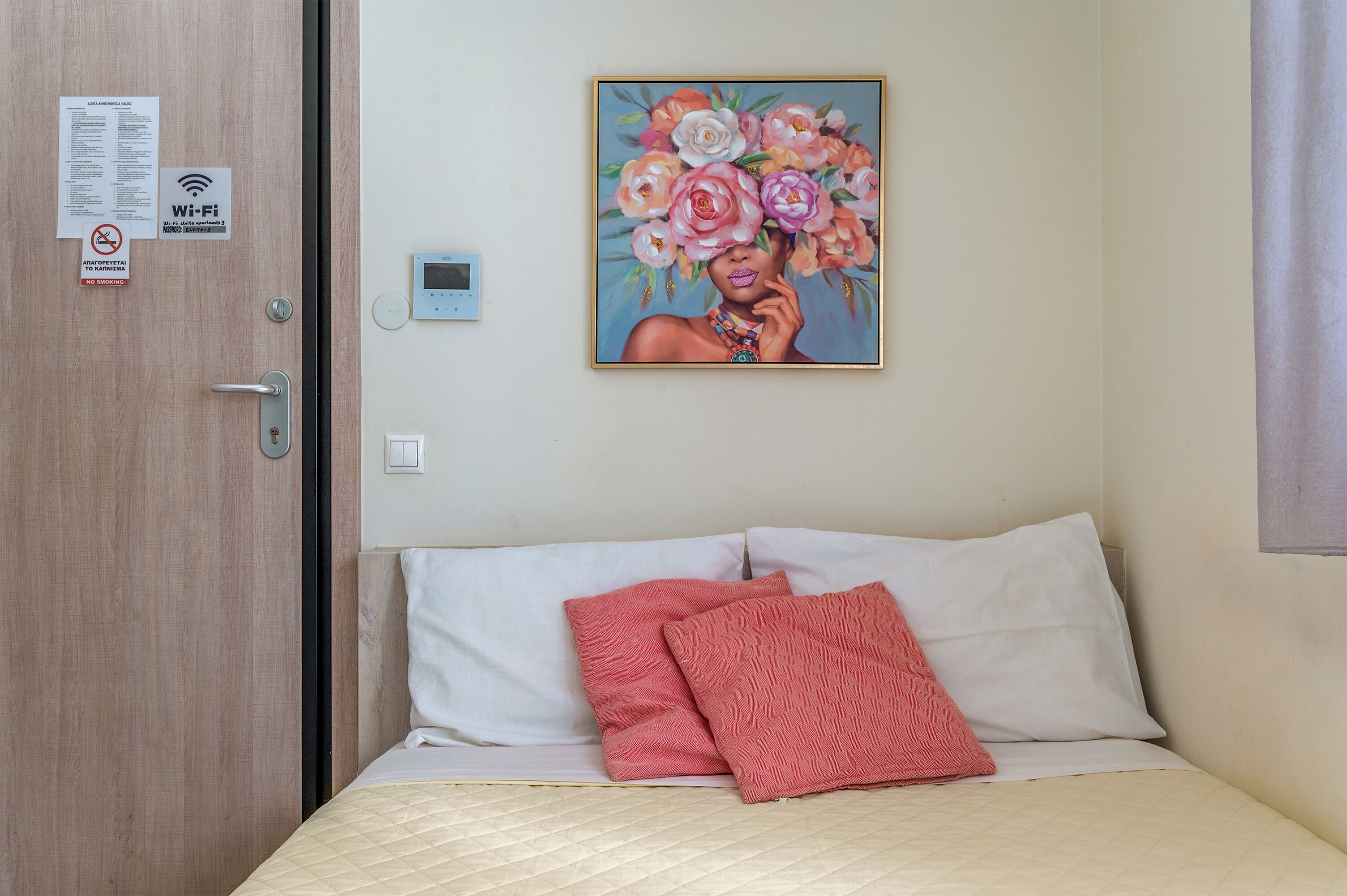 Una habitación de hotel con una cama, un cuadro en la pared, una puerta con el símbolo de Wi-Fi y un termostato.